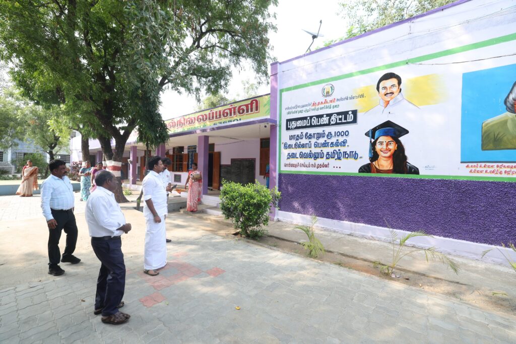 Anbil Mahesh enjoyingt the Puthumai Penn scheme ad on the school wall