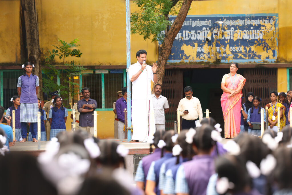 Minister addressing students at a government school assembly during 234/77 visit