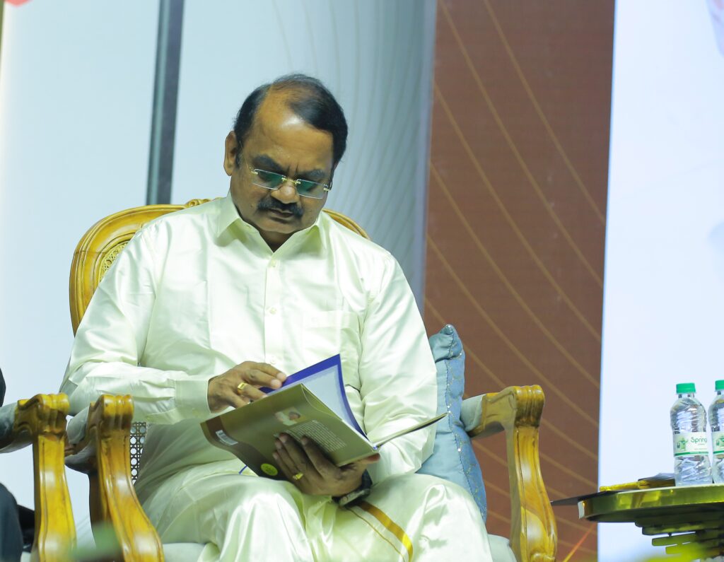 Padma Shri awardee Dr. Mylswamy Annadurai seated on stage reading "Madhayaanai" attentively during the book launch ceremony at Anna Centenary Library.