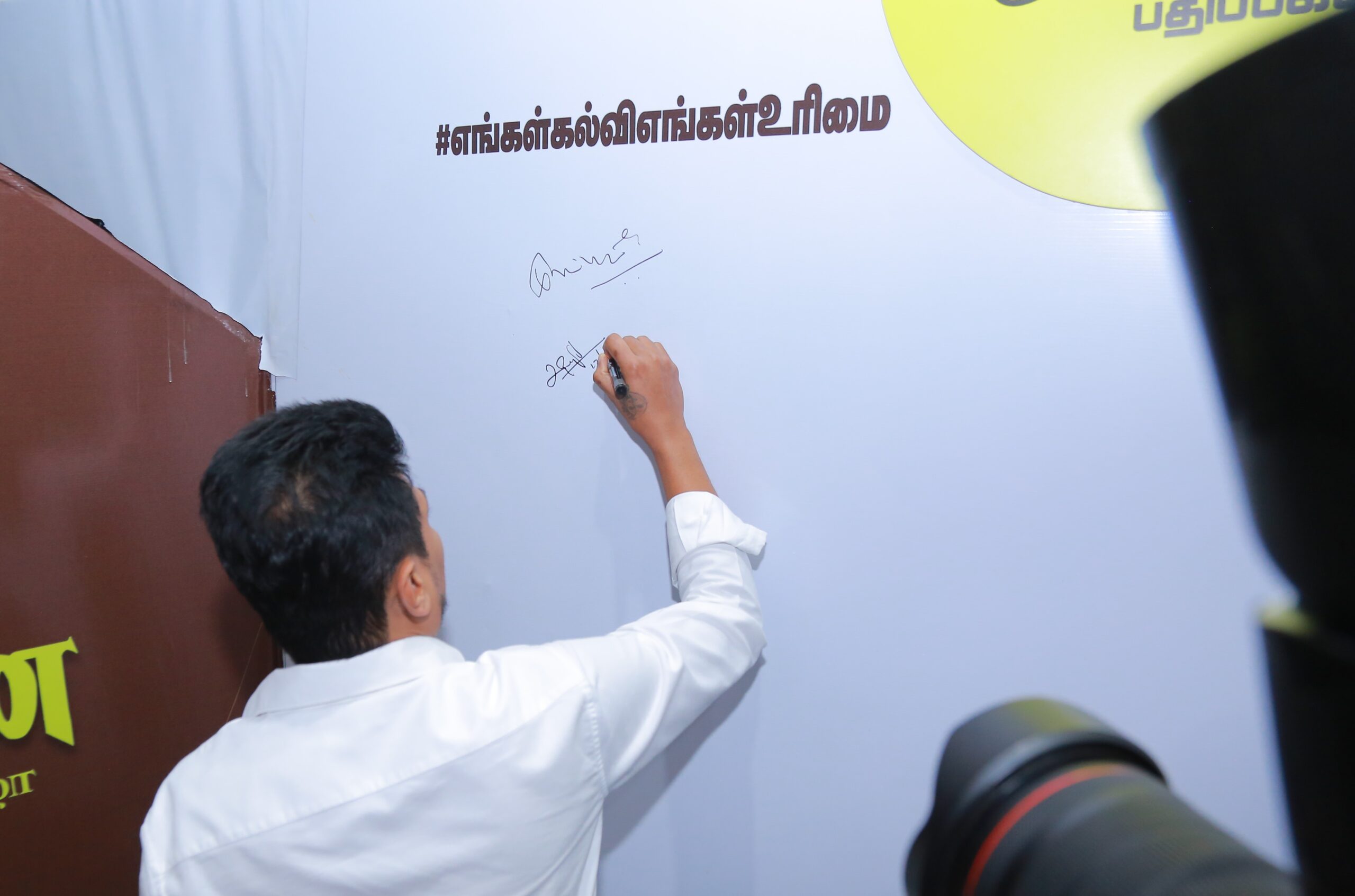 Udhayanidhi Stalin signing the pledge wall, supporting the message of educational autonomy and opposition to NEP 2020.
