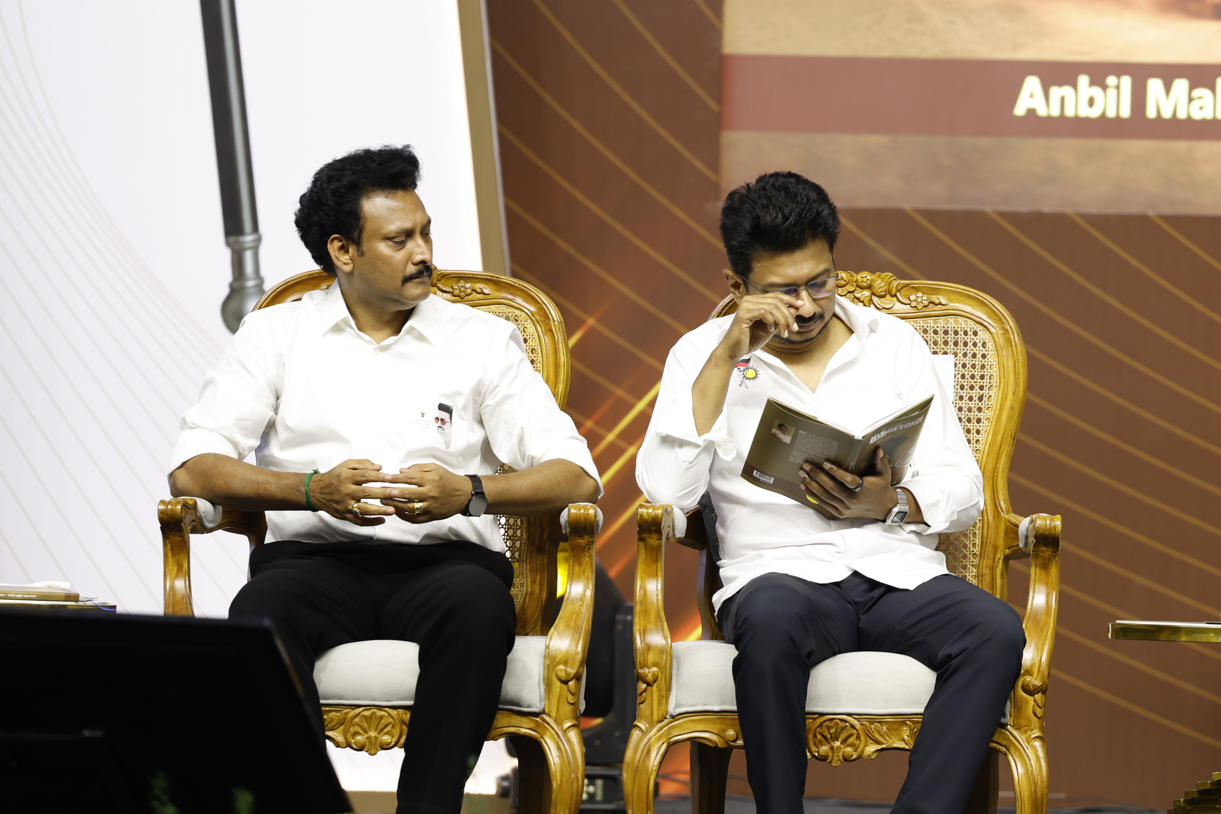 Minister Anbil Mahesh Poyyamozhi looking on while Udhayanidhi Stalin reads through the pages of the book "Madhayaanai" at the release function.