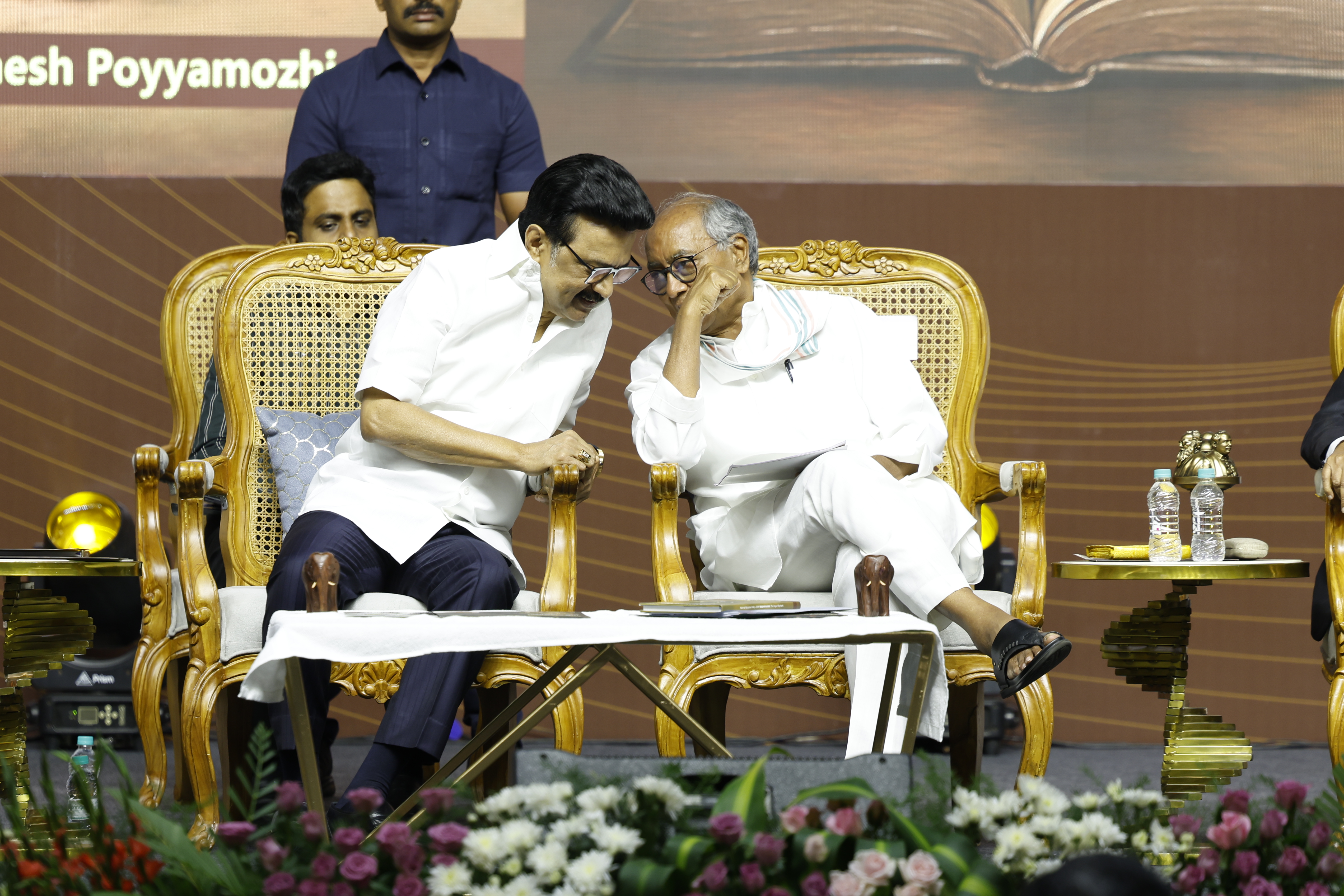 Chief Minister M.K. Stalin and Digvijaya Singh engaged in a thoughtful conversation during the "Madhayaanai" book launch, seated on stage amid floral arrangements.