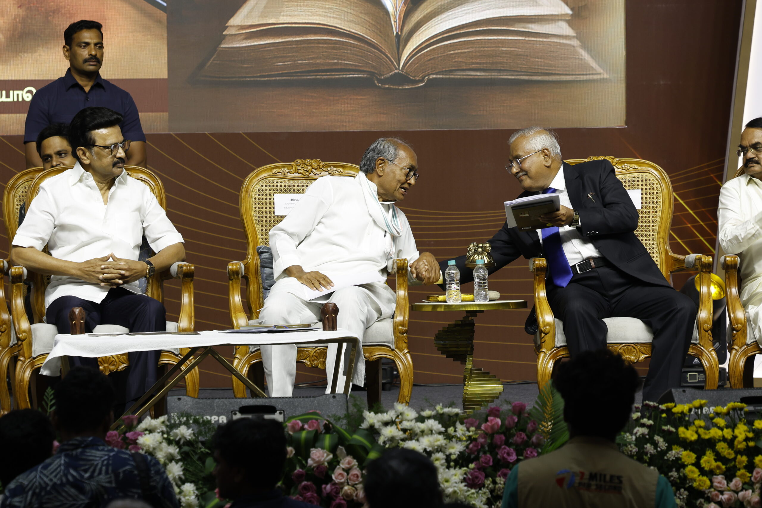 Digvijaya Singh and V. Gopala Gowda exchange views while holding copies of "Madhayaanai," seated beside Chief Minister M. K. Stalin during the release function.