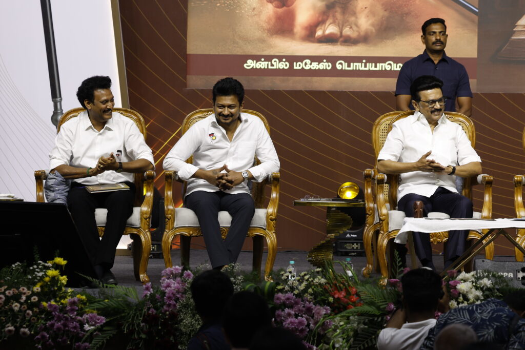Anbil Mahesh Poyyamozhi, Udhayanidhi Stalin, and M. K. Stalin share a light moment on stage while attending the launch of the bilingual book "Madhayaanai."